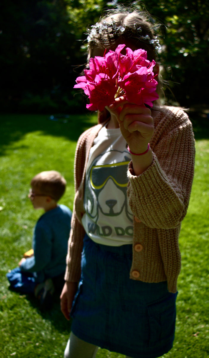 Kind trägt LOUCA Rock mit Blume - natürliche Kindermode Outdoor